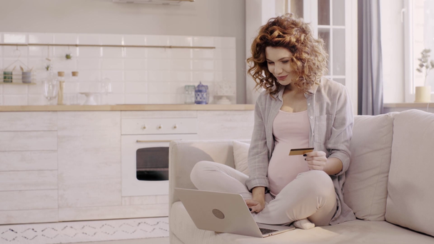 mujer embarazada feliz usando el ordenador portátil y la celebración de la tarjeta de crédito en pose de loto
 - Metraje, vídeo