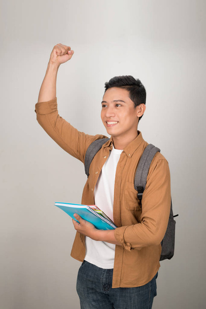 Yakışıklı Asyalı heyecanlı öğrenci mutlu bir gülümsemeyle beyaz arka planda izole edilmiş kameraya bakıyor. - Fotoğraf, Görsel