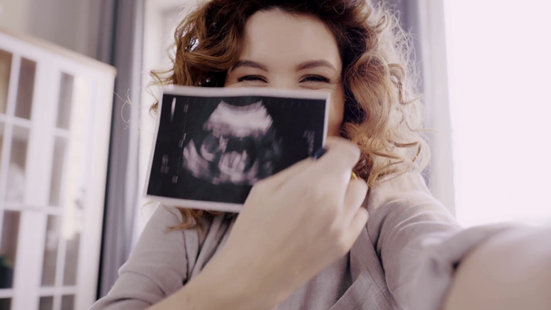 Schwangere zeigt Ultraschallbild des Fötus vor Kamera - Filmmaterial, Video