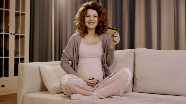 glücklich schwangere Frau mit Kreditkarte streichelt Bauch in Lotus-Pose - Filmmaterial, Video
