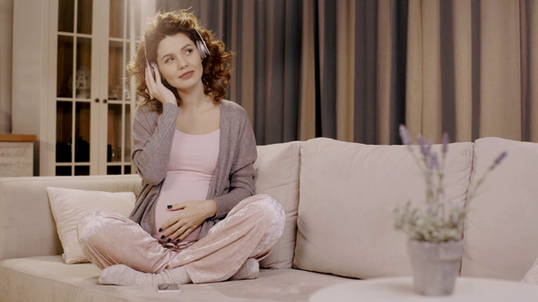 selectieve focus van plant en zwangere vrouw luisteren muziek in lotus poseren - Video