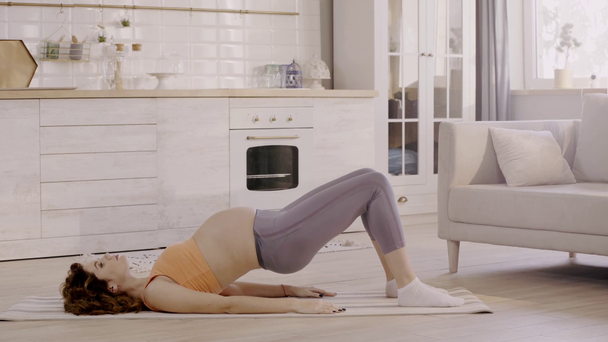 вид сбоку беременной женщины, занимающейся дома на фитнес-коврике
 - Кадры, видео