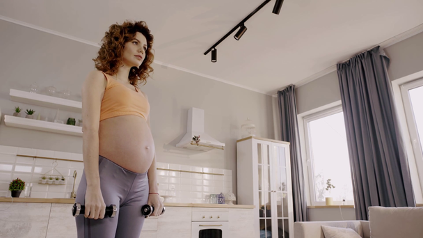 matala kulma näkymä raskaana oleva nainen käyttää kotona käsipainot
 - Materiaali, video