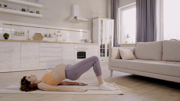 widok z boku ciężarnej kobiety ćwiczącej w domu na macie fitness - Materiał filmowy, wideo