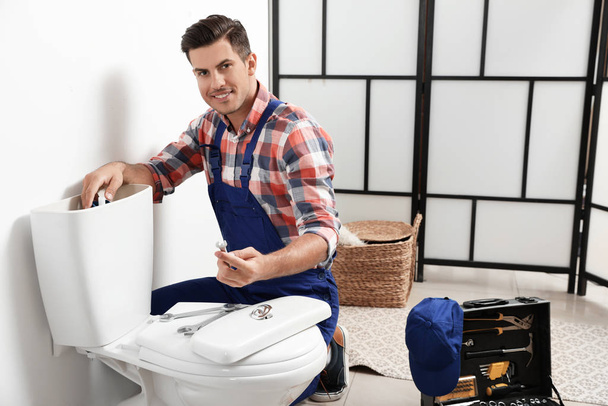Professional plumber working with toilet bowl in bathroom - Foto, Imagem
