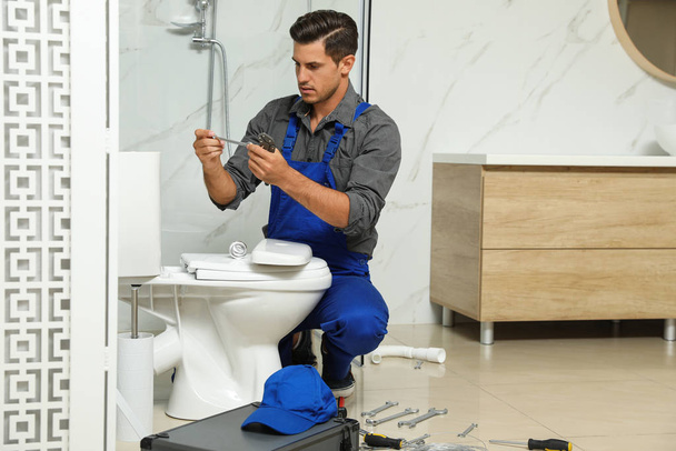 Professional plumber working with toilet bowl in bathroom - Fotoğraf, Görsel