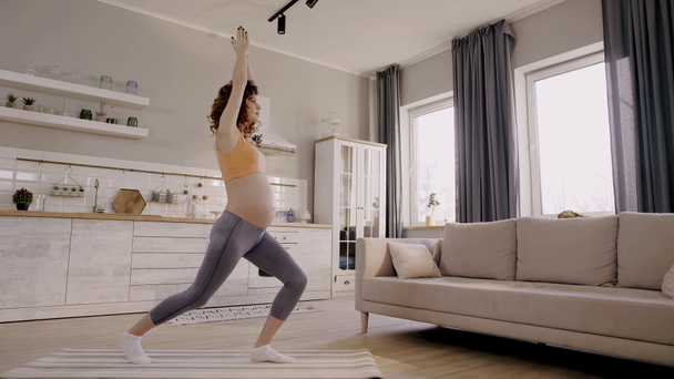 widok z boku ciężarnej kobiety ćwiczącej jogę w domu - Materiał filmowy, wideo