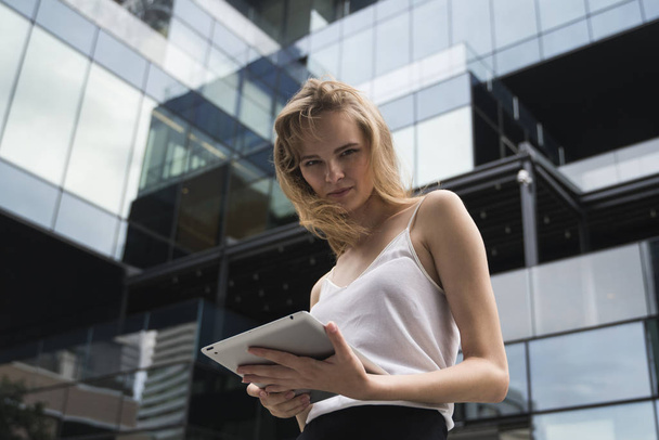 Portrait of business woman holding a tablet computer. Business woman on a meeting and waiting business partner and holding a tablet in hands. - Фото, изображение