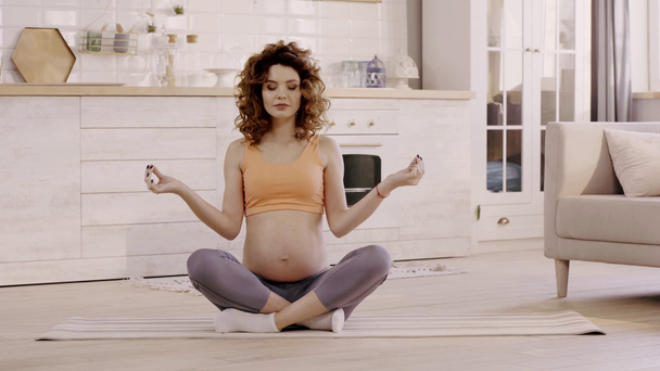 pregnant woman meditating in lotus pose at home on yoga mat - Video, Çekim