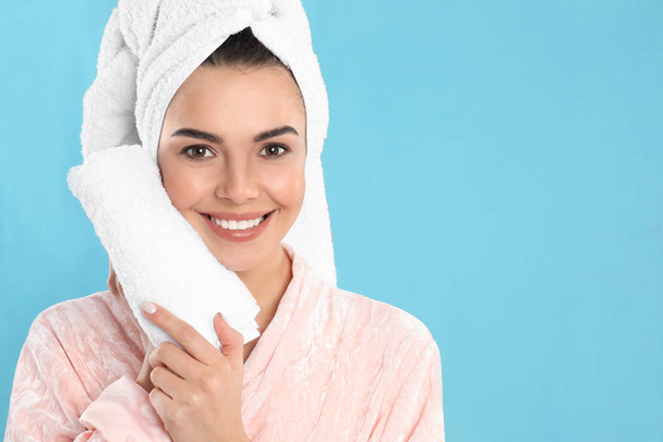 Young woman wiping face with towel on light blue background. Space for text - Foto, Bild