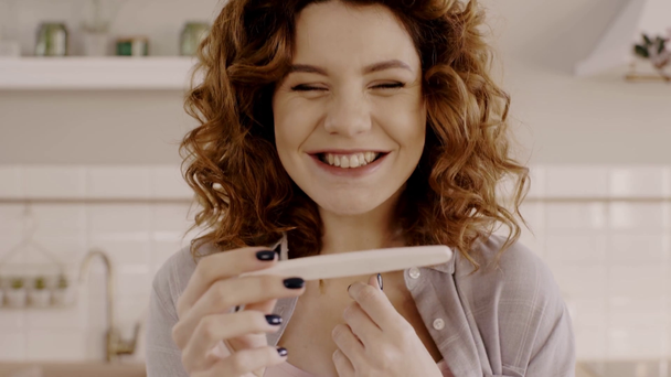 zaskoczona szczęśliwa kobieta w ciąży patrząc na test ciążowy - Materiał filmowy, wideo