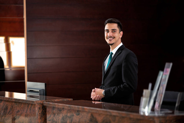 Young receptionist standing behind the front desk  - Foto, Bild