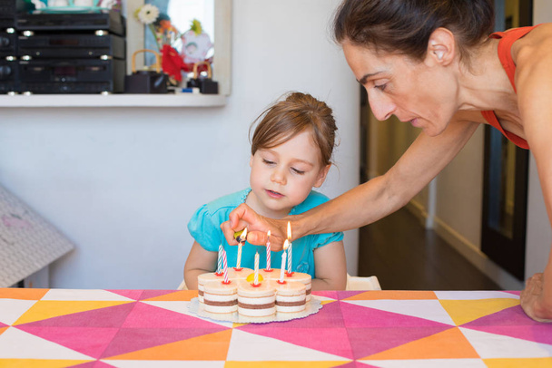 woman lighting candles on birthday cake and child looking - Fotoğraf, Görsel