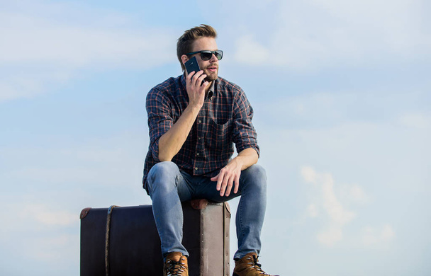 nice talk. traveler wait for taxi. Move. male fashion style. looking so trendy. businessman in glasses. business trip. macho man tourist relax tour bag. sexy man sky background speak on phone - Foto, imagen