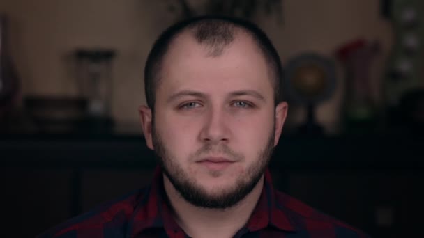 Upset offended young guy of European appearance sits in a chair in a plaid shirt. Emotion concept - Footage, Video