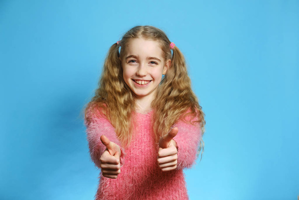 Joyful blonde girl isolated smiling. The girl is dressed in a pink sweater. - Photo, Image