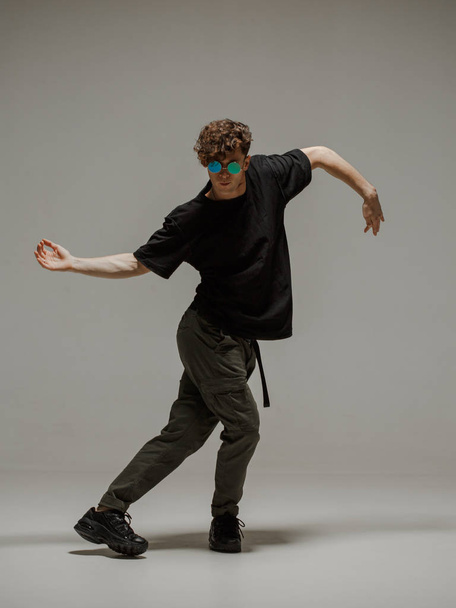 Guy dancing contemporary dance in studio. Neutral grey background. Acrobatic bboy dancer. - Φωτογραφία, εικόνα