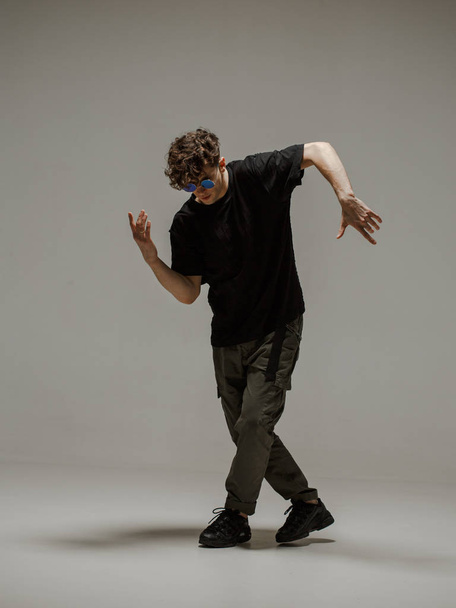 Guy dancing contemporary dance in studio. Neutral grey background. Acrobatic bboy dancer. - Foto, afbeelding