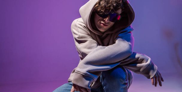 Modern Epic portrait of bboy in a neon light hoodie. Beneath the hood. Dark face. Mysterious and cool. - Foto, immagini