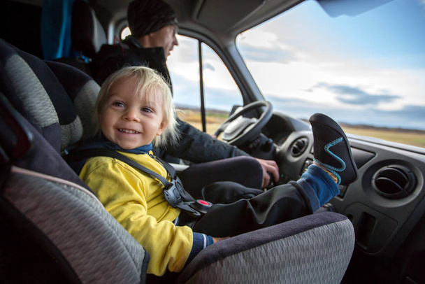 Симпатичний хлопчик-малюк, дитина сидить на передньому сидінні в дитячому кріслі на великому фургоні, щасливо посміхаючись
 - Фото, зображення