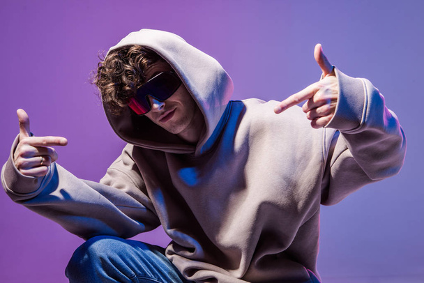 Modern Epic portrait of bboy in a neon light hoodie. Beneath the hood. Dark face. Mysterious and cool. - Фото, изображение