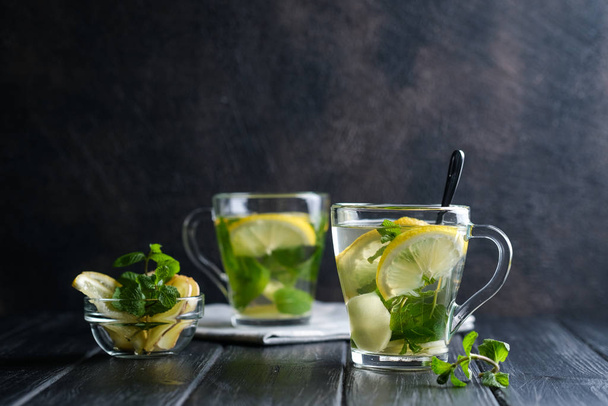 Fresh ginger tea with lemon slices, mint and honey on a dark background. - Zdjęcie, obraz