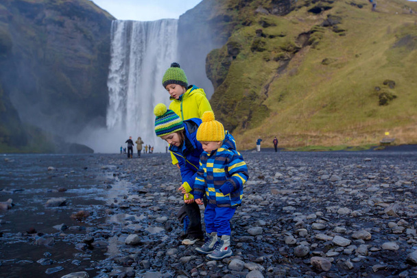 Cute child playing in front of the Skogafoss waterfall in Icelan - Fotó, kép
