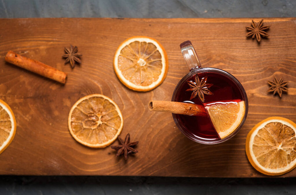 winter spicy drink mulled wine based on red wine, spices and orange. on a dark wooden background. close-up, space for text . the view from the top - Zdjęcie, obraz