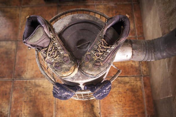 Wet used boots and socks drying over firewood stove - Fotoğraf, Görsel