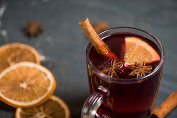 winter spicy alcoholic mulled wine based on red wine, spices and orange. on a dark background . close-up, macro photo . space for text . the view from the top - 写真・画像