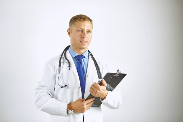 Νεαρός γιατρός με αυτοπεποίθηση σε λευκό παλτό με στηθοσκόπιο - Φωτογραφία, εικόνα