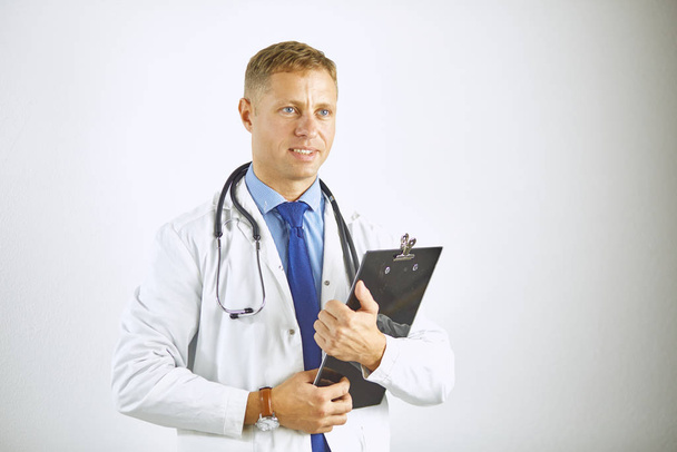Молодой уверенный доктор в белом халате со стетоскопом - Фото, изображение