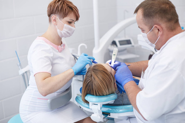 Médecin dentiste traite les dents d'une belle jeune fille patiente. La fille à la réception chez le dentiste. Médecin dentiste soigne les dents - Photo, image
