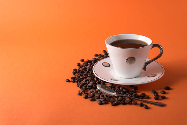 šálek aromatické kávy a kávových zrn na oranžovém trendy pozadí s prostorem pro text - Fotografie, Obrázek