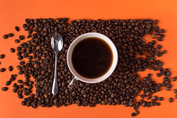 šálek aromatické kávy a kávových zrn na oranžovém trendy pozadí s prostorem pro text - Fotografie, Obrázek