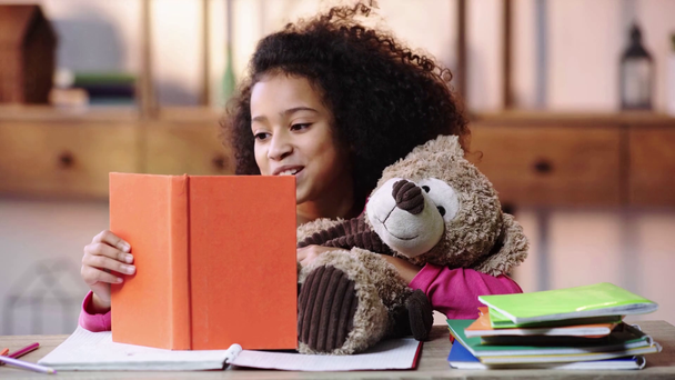 glimlachend Afrikaans amerikaans kind lezen boek aan teddy beer - Video