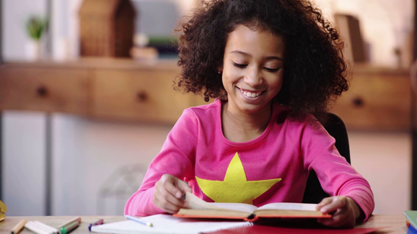 criança afro-americana rindo enquanto lia o livro
 - Filmagem, Vídeo