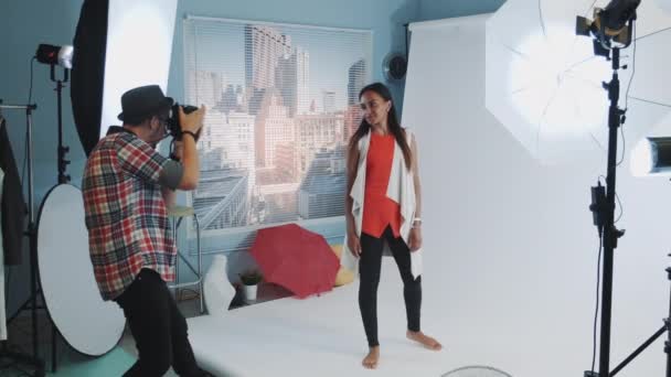 Hermosa chica de raza mixta posando para el fotógrafo en sesión de fotos de estudio profesional
 - Metraje, vídeo