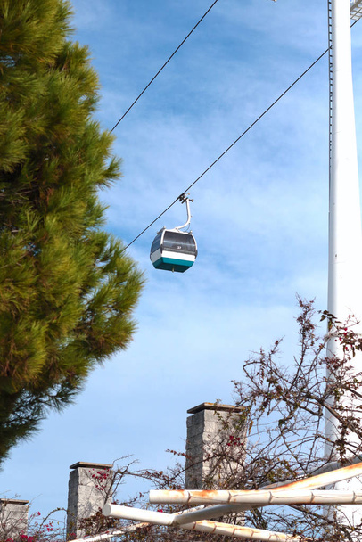 Petites cabines funiculaires électriques dans le ciel bleu au-dessus de la promenade près du parc avec des arbres verts en été. Telecabina
  - Photo, image