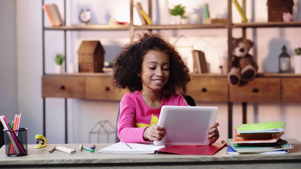 wstrząśnięte i śmiejące się amerykańskie dziecko korzystające z tabletu cyfrowego - Materiał filmowy, wideo