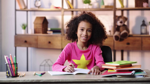 sorridente bambino afroamericano che fa i compiti e agita la mano
 - Filmati, video