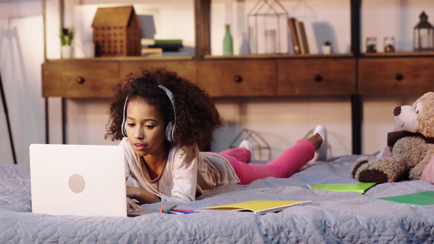 afro-américaine enfant ayant appel vidéo sur ordinateur portable au lit
 - Séquence, vidéo
