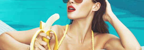 Sexy woman in swimming pool eating banana widescreen banner - Fotó, kép