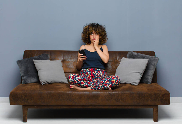 young pretty woman at home, with a mobile phone, wearing pajamas - Fotó, kép