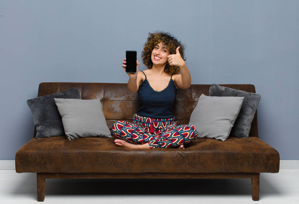 young pretty woman at home, with a mobile phone, wearing pajamas - Fotó, kép