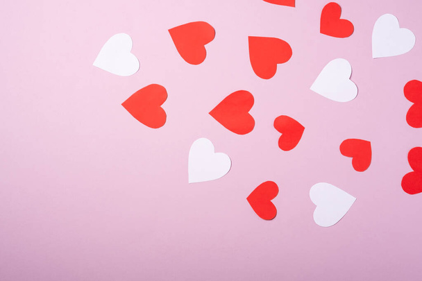 Red and white handmade paper hearts valentines on pink background, copy space, top view - 写真・画像