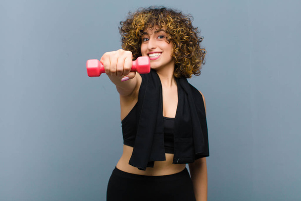young pretty sports woman wearing fitness clothes lifting a dumbbell - Fotó, kép