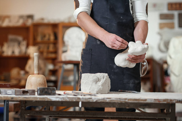 Craftsman hands working with stone sculptor at creative workplace in the atmospheric studio. - Foto, Imagen