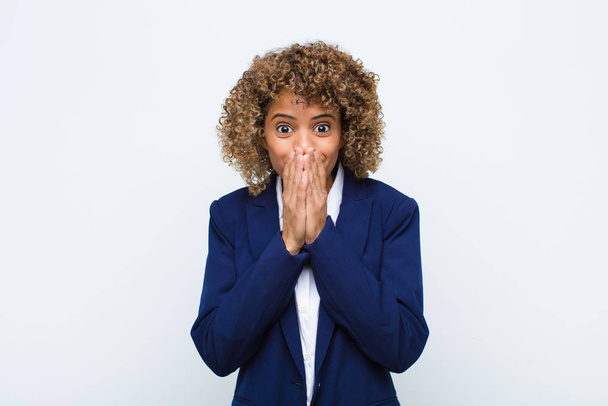 young woman african american happy and excited, surprised and amazed covering mouth with hands, giggling with a cute expression against flat wall - Fotoğraf, Görsel