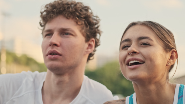 Γκρο πλαν άποψη του Carefree ευτυχισμένη σγουρά αρσενικό τενίστας κοιτάζοντας μακριά και έχοντας υπόλοιπο μαζί με την ευτυχισμένη γυναίκα αντίπαλό του στο γήπεδο τένις - Πλάνα, βίντεο